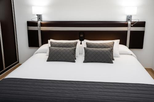 a bedroom with a large white bed with two pillows at HOSTAL LAS PALOMAS in Lucena