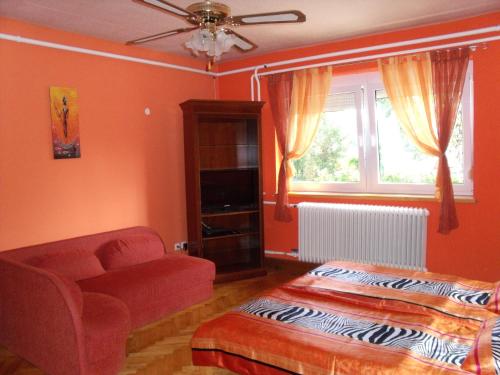 a bedroom with a bed and a chair and a window at Viola Vendégház in Kehidakustány