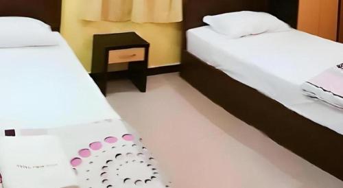 a room with two beds and a night stand with at Twin Star Hotel in Tanjung Malim