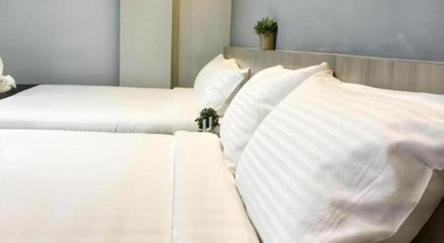 two white beds with white pillows in a bedroom at Kimal Hotel Taiping in Taiping