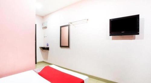 a room with a television and a red rug at OYO 89539 Hotel Siswa in Kampar