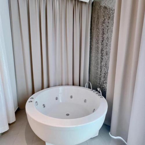 a white bath tub in a bathroom with curtains at S Hotel in Johor Bahru