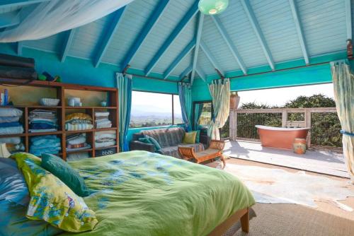 ein blaues Schlafzimmer mit einem Bett und einem Balkon in der Unterkunft Bali Bliss Villa - Golden Bay in Takaka