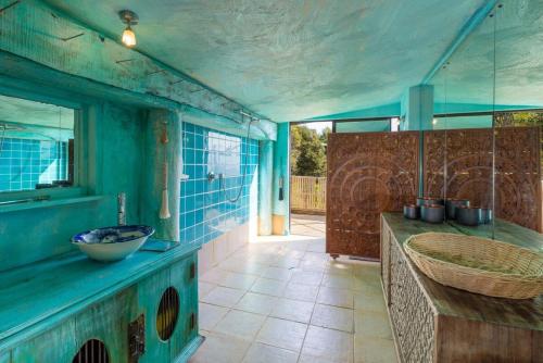 ein blaues Badezimmer mit Waschbecken und Spiegel in der Unterkunft Bali Bliss Villa - Golden Bay in Takaka