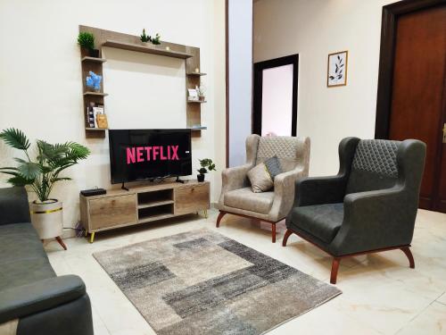 a living room with a tv and two chairs at Royal central home Cairo in Cairo