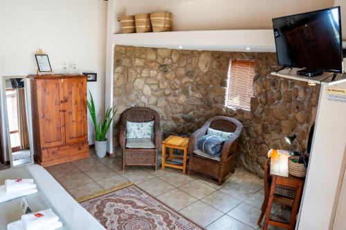 a living room with two chairs and a tv at 7th Hole Golf Lodge in Modimolle