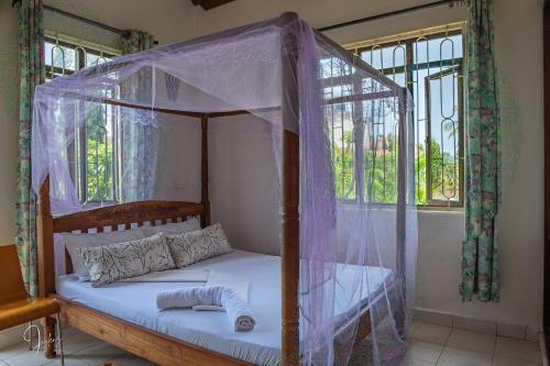 a bed with a canopy in a room with windows at Mtwapa Curtie Home in Mombasa