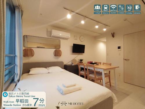 a bedroom with a bed and a table and a desk at Mi-HOTEL KAGURAZAKA in Tokyo