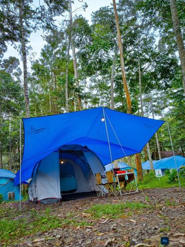 a blue tent with chairs and a table in the forest at Be Glamping Lembang in Lembang