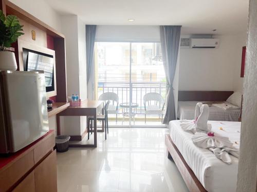 a hotel room with a bed and a television and a balcony at Arisa Hotel Patong Beach in Patong Beach