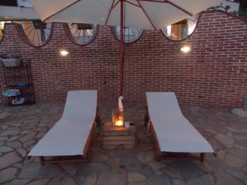 two benches and an umbrella on a patio at B&B Pacilita in Pianopoli