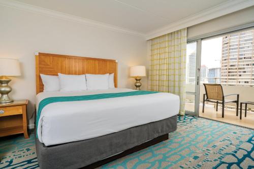 a hotel room with a large bed and a balcony at Waikiki Marina Resort at the Ilikai in Honolulu