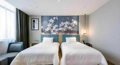 a room with two beds and a chair and a painting at Magnotel Hotel Dongxing Guomen Port in Fangcheng