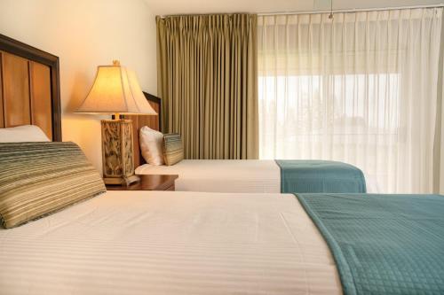 a hotel room with two beds and a window at Paniolo Greens Resort in Waikoloa