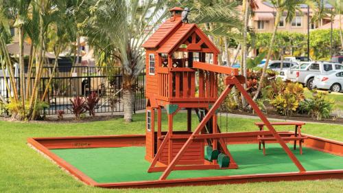 a playground with a play structure on the grass at Kona Coast Resort in Kailua-Kona