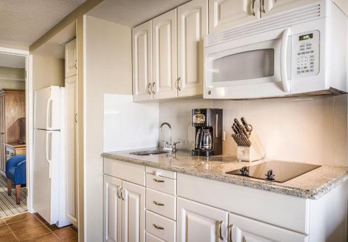 a kitchen with white cabinets and a white microwave at Club Wyndham Inn on Long Wharf in Newport
