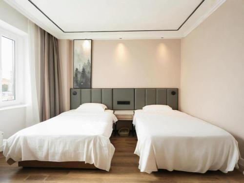 two beds in a room with white walls at GreenTree Inn Langfang Sanhe South Yingbin Road Express Hotel in Sanhe