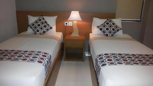 a hotel room with two beds and a lamp at MANDARI HOTEL SINGARAJA in Ubud
