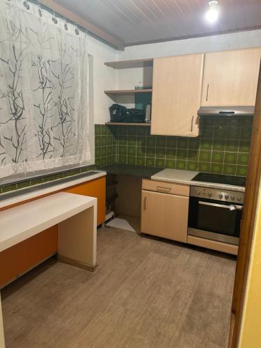a small kitchen with a stove and green tiles at WG Riedau in Riedau