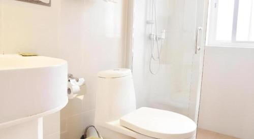 a white bathroom with a toilet and a shower at London Hotel in Macau