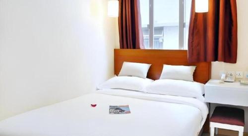 a bedroom with a white bed with a desk and a window at London Hotel in Macau