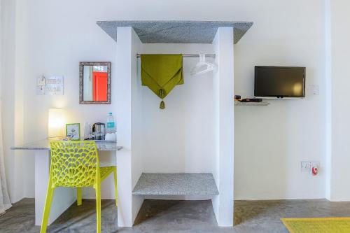 a room with a yellow chair and a desk with a television at Itsy Hotels Red Lotus Heritage, Promenade Beach in Puducherry