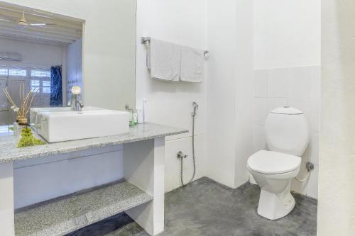 a white bathroom with a toilet and a sink at Itsy Hotels Red Lotus Heritage, Promenade Beach in Puducherry