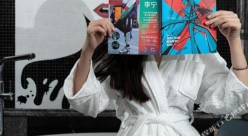 a woman in a white dress holding a book at Ethos Hotel Wuhan Riverside in Wuhan