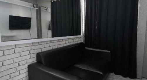 a black couch in a room with a mirror at OYO Living 3091 Apt The Suites Metro By Ananda in Bandung
