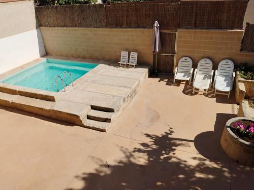 an empty swimming pool with chairs and an umbrella at Casa Remunda in Torregrossa