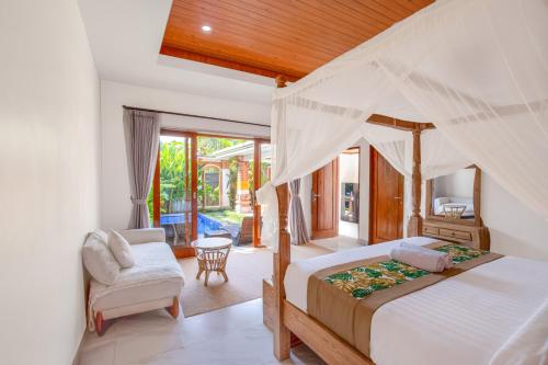 a bedroom with a canopy bed and a chair at Ubud Arindra Private Pool Villa in Ubud