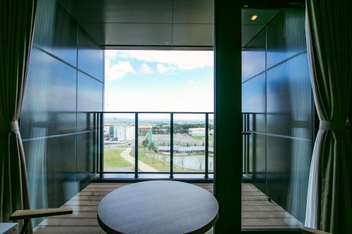 a balcony with a table and a large window at tower eleven hotel in Kitahiroshima