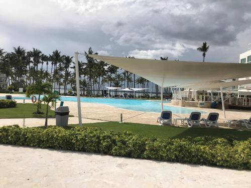 a pool at a resort with chairs and a white canopy at Residencial la ensenada, on Playa Nueva Romana in Boca del Soco