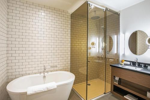 a bathroom with a tub and a shower and a sink at Sandman Signature Aberdeen Hotel & Spa in Aberdeen