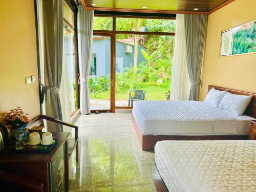 a bedroom with two beds and a large window at Hidden Rock Tam Coc in Vũ Lâm