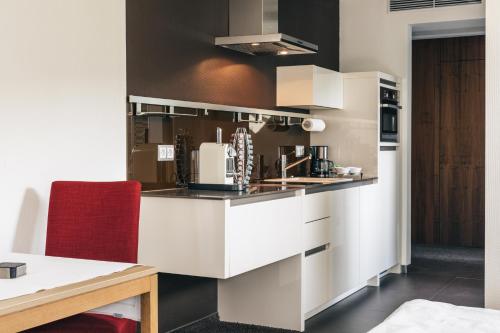 a kitchen with white cabinets and a red chair at Consulat des Weins in Sankt Martin