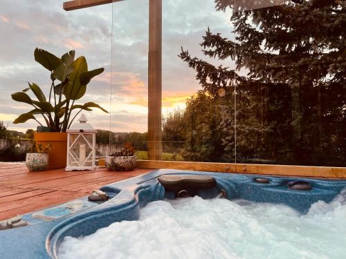 a hot tub in the snow on a deck at Logement indépendant la k abane en palette in Blandin