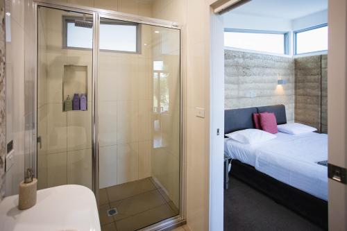 a bathroom with a shower and a bed and a tub at Eagle Peaks at Freycinet in Coles Bay