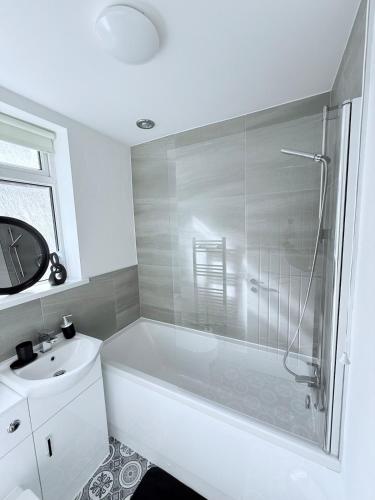 a bathroom with a white tub and a sink at Seaside Home - Spacious Rooms - TV's in Every Room in Cleethorpes
