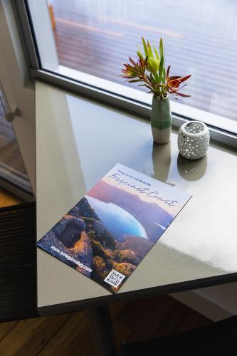 a book on a table with a vase of flowers at Eagle Peaks at Freycinet in Coles Bay
