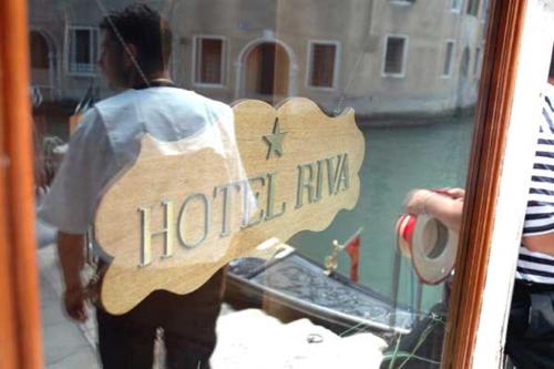 Una persona está mirando un barco en una ventana. en Hotel Riva, en Venecia