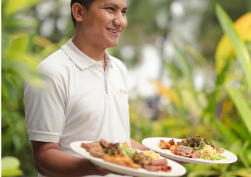 a man is holding two plates of food at Seasalter Maldives in Hulhumale