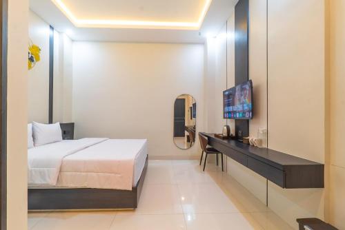 a bedroom with a bed and a desk and a television at Gomini Stay in Cebongan