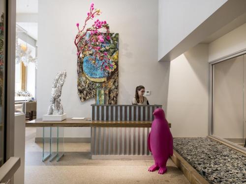 a woman sitting at a reception desk in a room with a pink dog at 21c Museum Hotel Durham in Durham