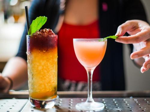 a person is putting a green leaf into a drink at 21c Museum Hotel Durham in Durham