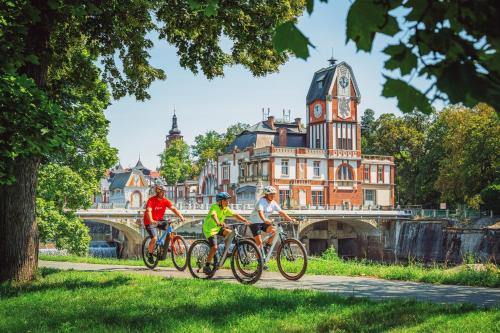 three people riding bikes on a path in front of a bridge at Apartment Holata 201 in Hradec Králové
