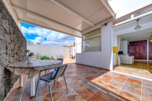 Un patio con mesa y sillas y un muro de piedra. en Casa Bom, en Tahiche