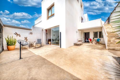 Un patio en una casa blanca con sillas y mesas. en Casa Bom, en Tahiche
