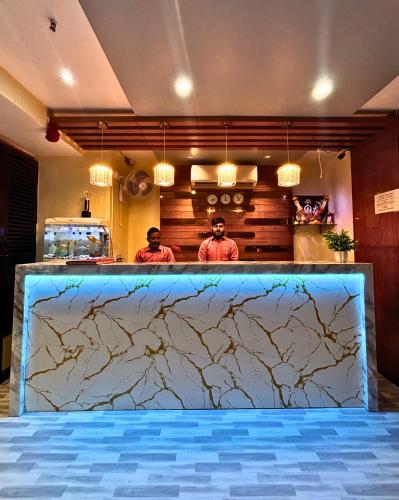 two men standing behind a counter in a kitchen at Hotel Ashraya International in Mumbai
