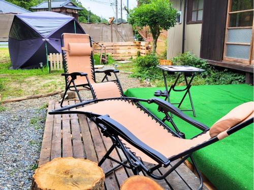 two chairs and a table in a backyard with a tent at 古民家サウナandバーベキュー TK亭 in Ichihara